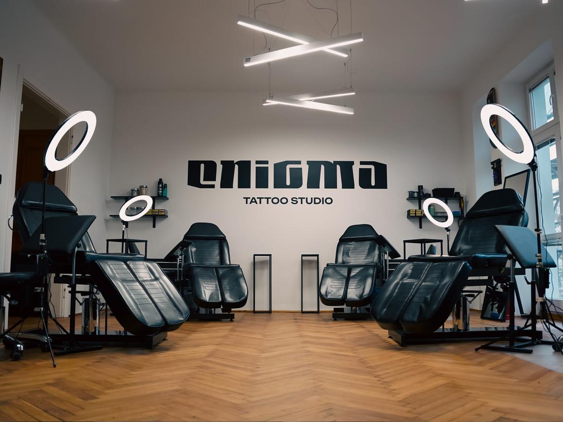 Tattoo room at Enigma studio with chairs and the logo on the wall
